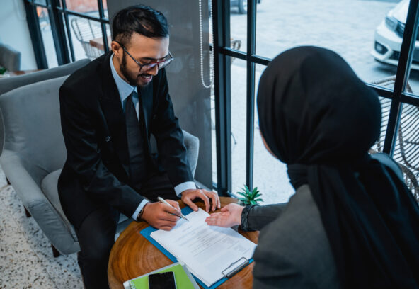 portrait of businessman signing an agreement letter during meeting with female muslim partner
