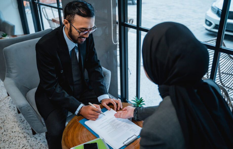 portrait of businessman signing an agreement letter during meeting with female muslim partner